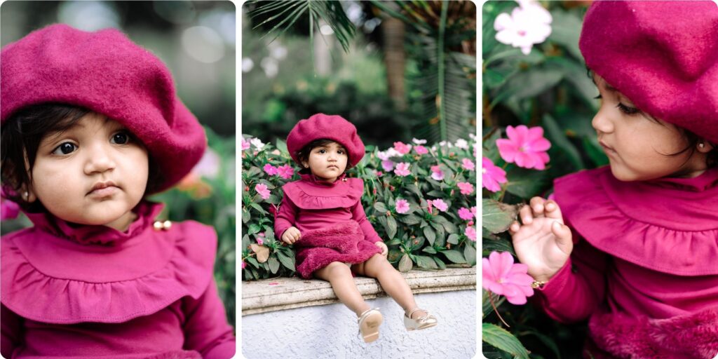 A toddler in a magenta beret and matching dress sits among bright flowers during her first birthday photoshoot in St. Pete, highlighting expressive close-up portraits and playful curiosity as she studies the blooms.