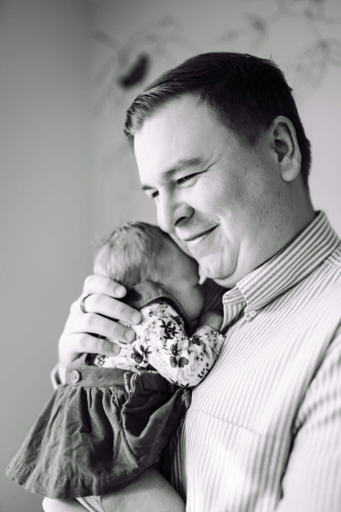 A dad looks proud as he holds his daughter