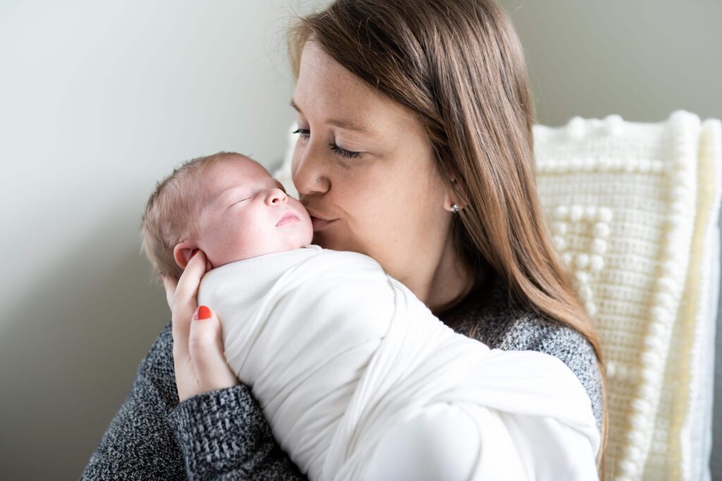 Mom kisses her newborn daughter as she sleeps
