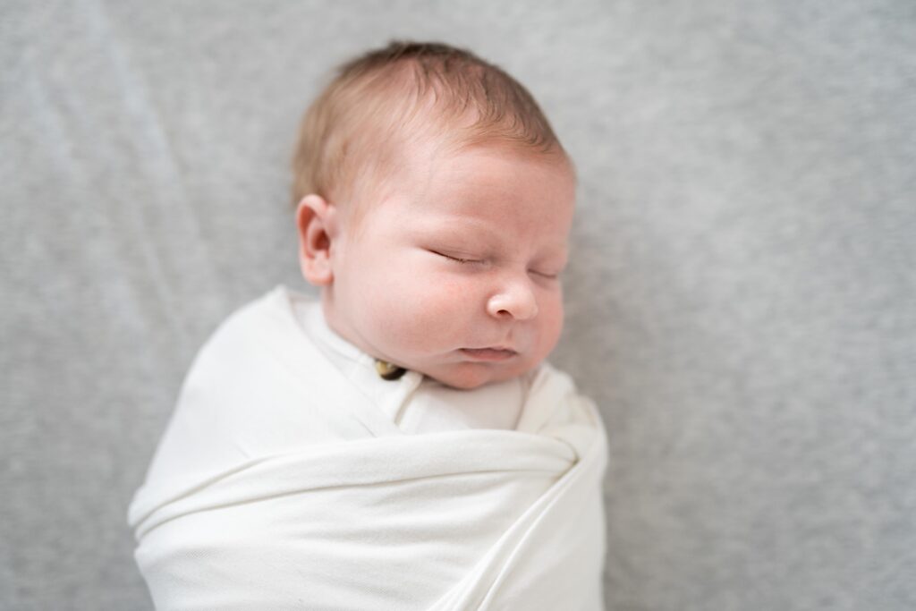 A little newborn baby sleeps in her crib, all swaddled up