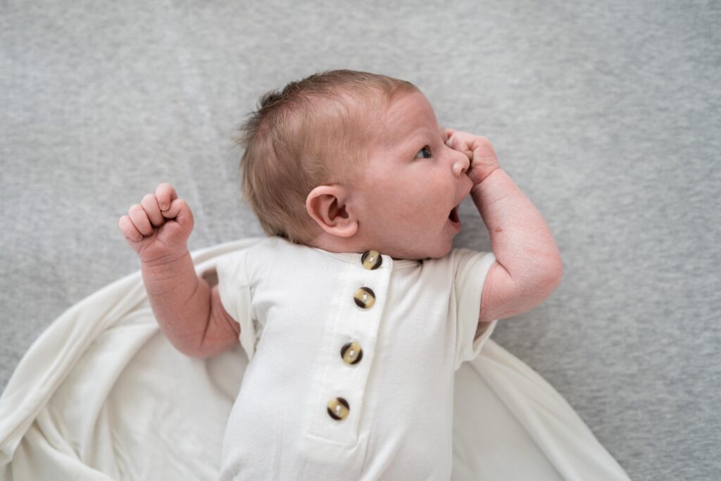 A newborn stretches as she is released from her swaddle wrap