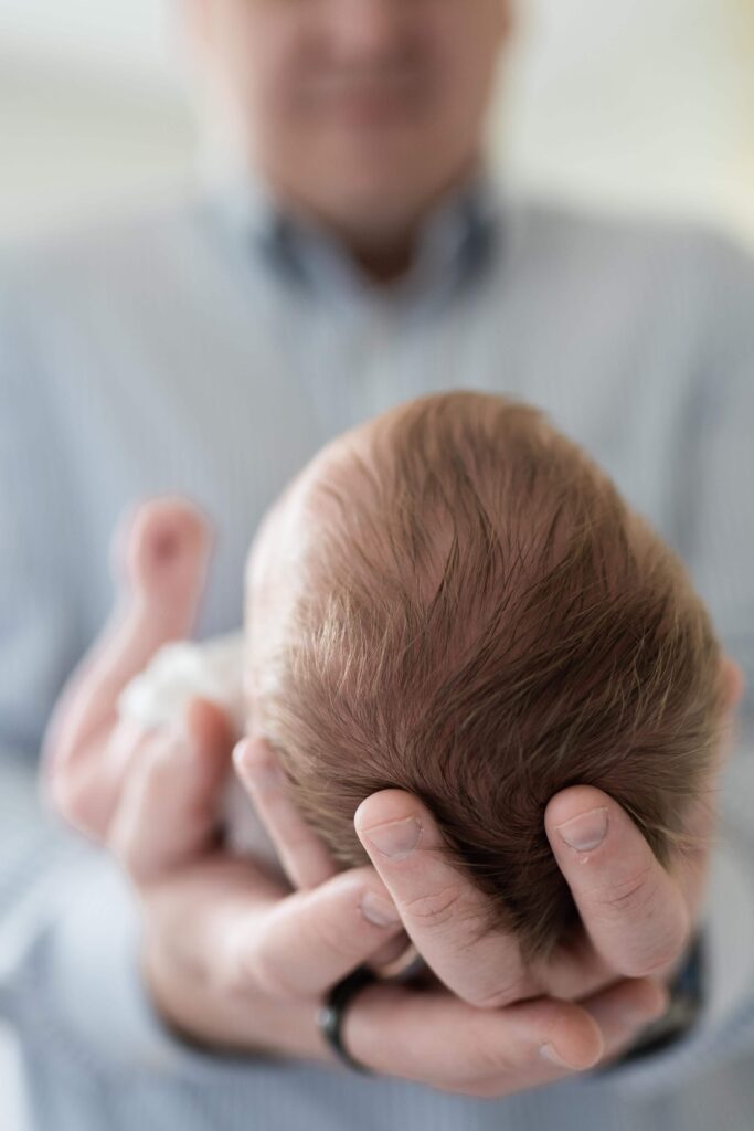 Baby girls' head being safely held in her daddy's arms