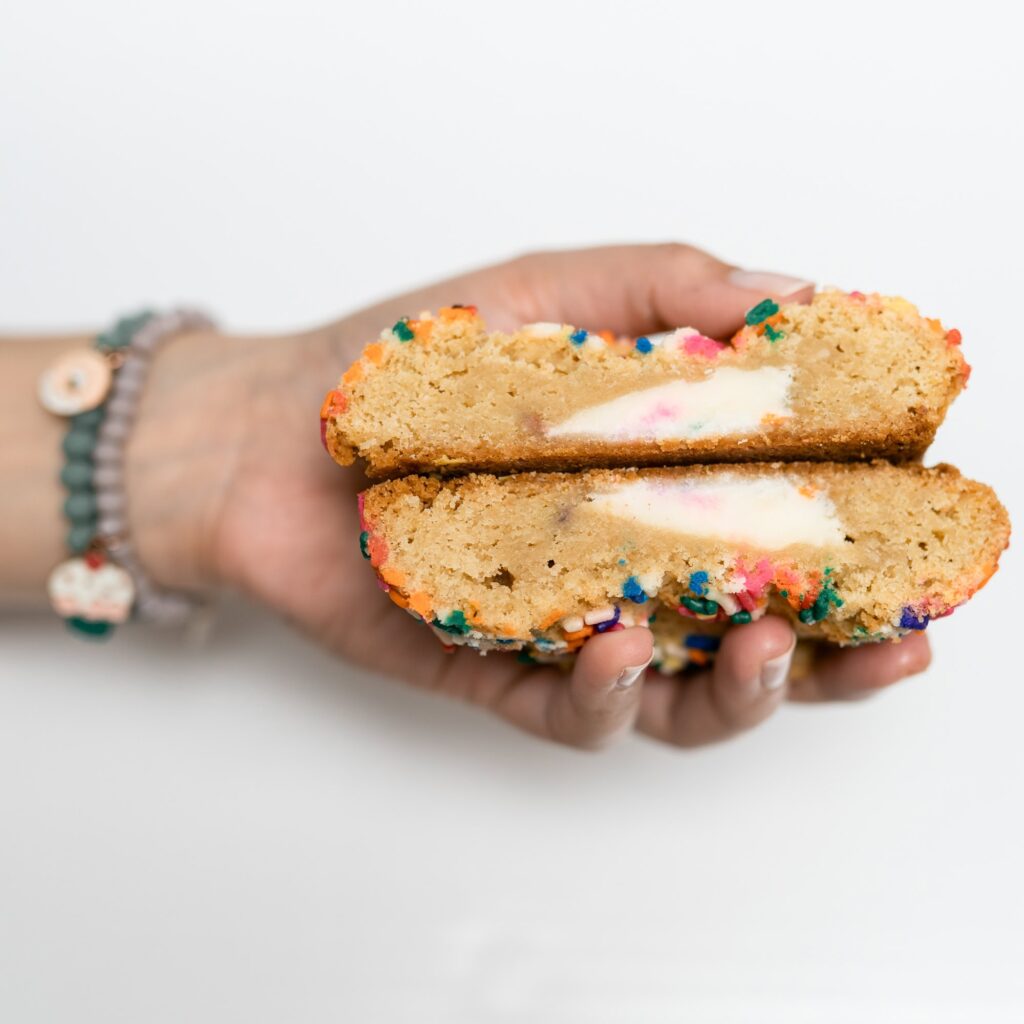 A giant stuffed sugar cookie with sprinkles is held by Chef Mel