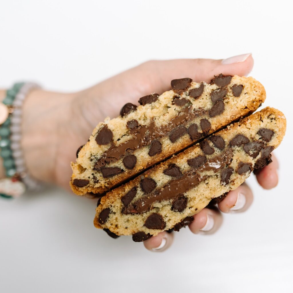 Chef Mel of CaraMel's Bakery holding a giant stuffed chocolate chip cookie