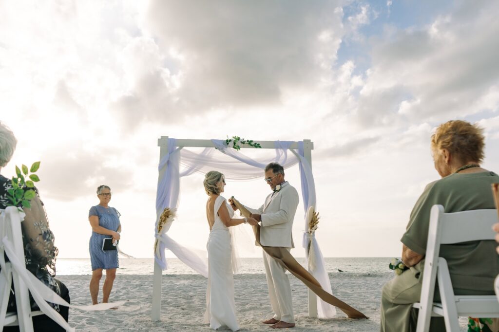 A groom unrolls his scroll of vows in the sunset