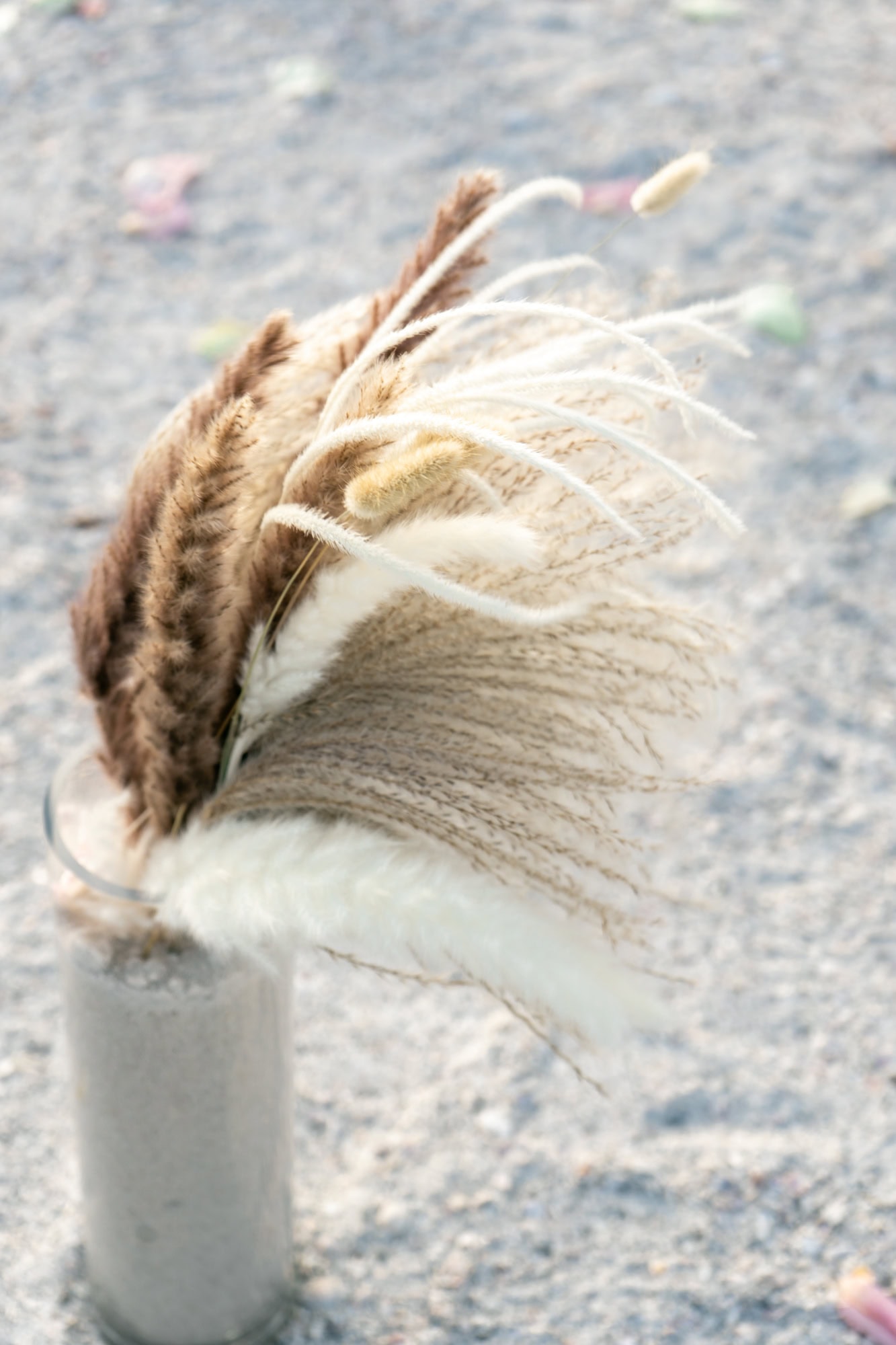 Details of the floral arrangements - a hurricane jar filled with sand keeps flowers upright even in windy conditions