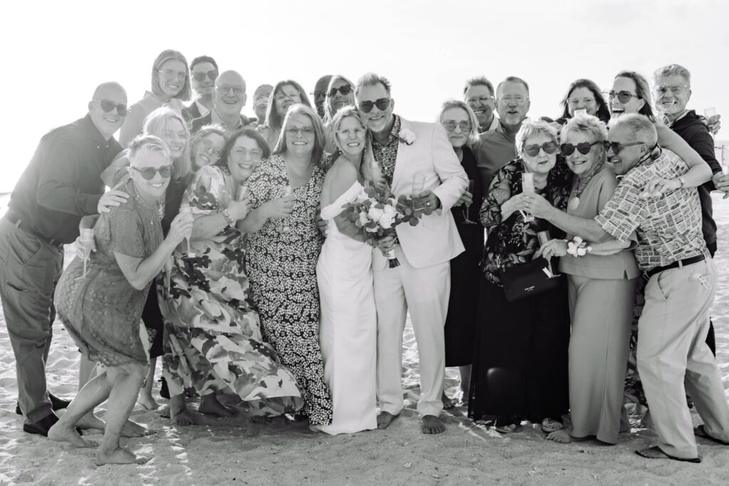 A group shot of the newlywed couple surrounded by all of their guests