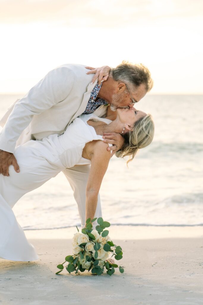 A groom dips his bride on the beach in a quiet moment after their ceremony