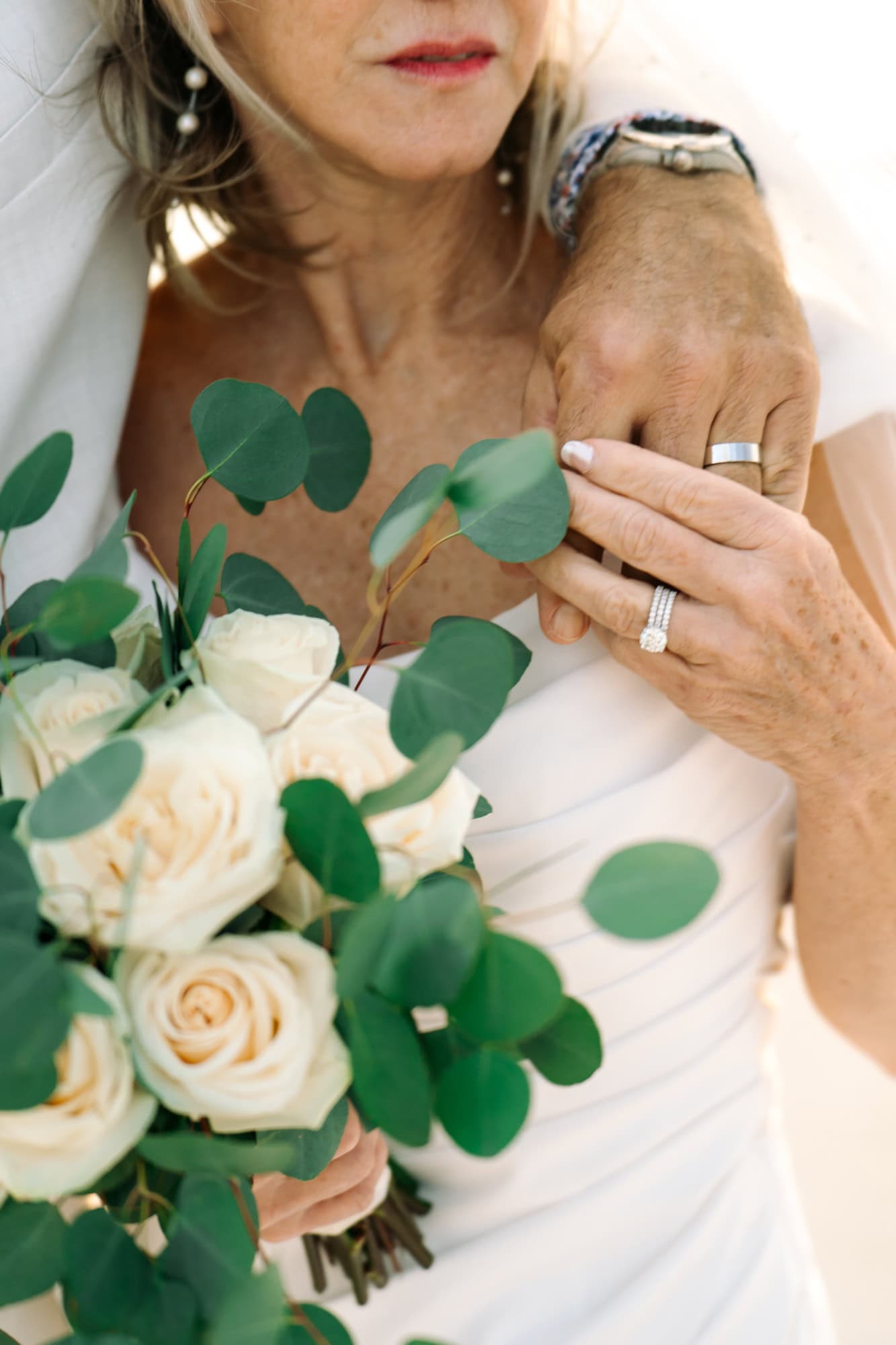 Detail shot of a couple's rings and bouquet during taken during their portrait session on the beach