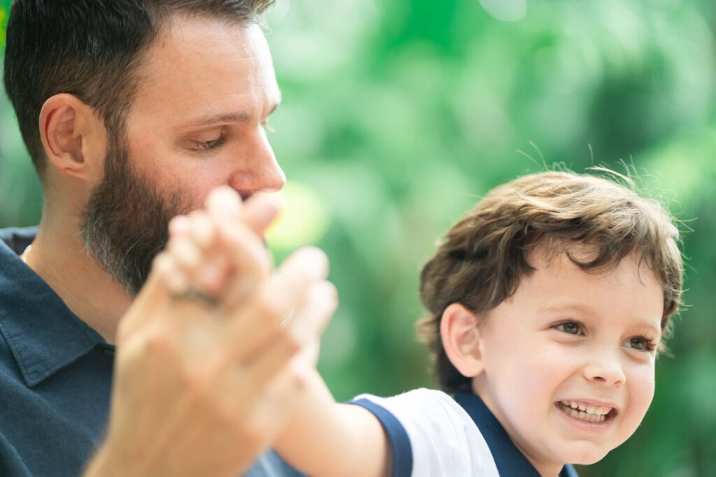 Father holding his son’s hand while the boy laughs during a Sunken Gardens family session in St. Petersburg