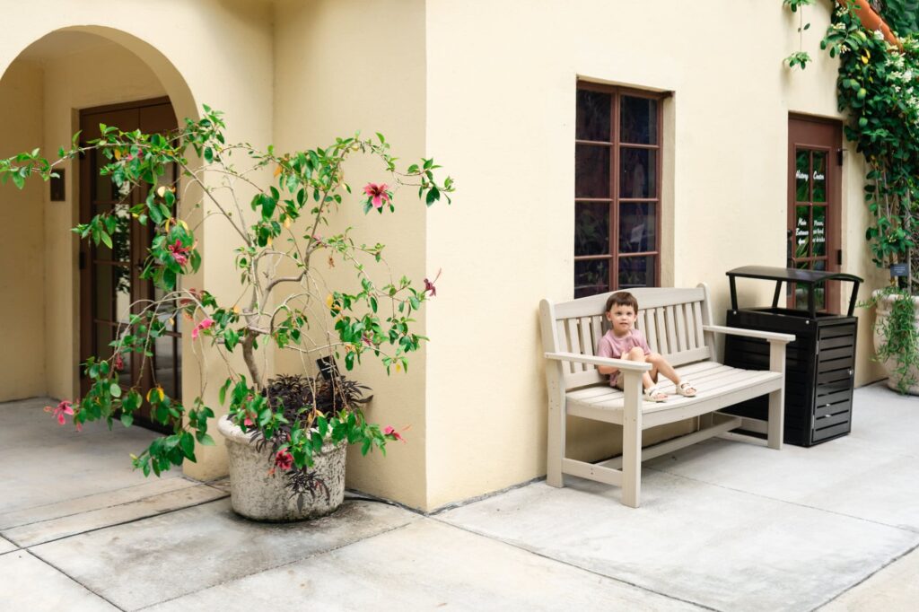 Young boy sitting on a bench outside the Sunken Gardens welcome center in St. Petersburg