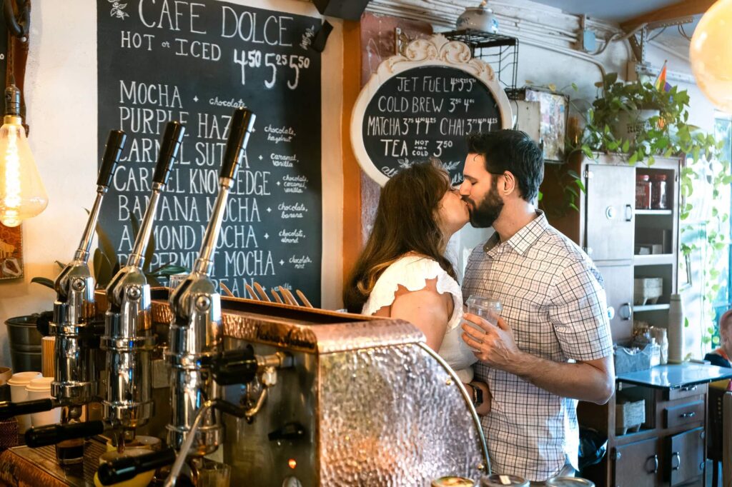 Couple sharing a kiss at the counter of a local coffee shop in St Petersburg, FL. A fun and personal engagement photo idea for couples who feel awkward with traditional poses.