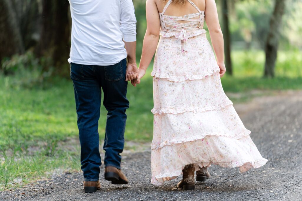 Close-up of a couple walking hand in hand down a dirt path in St Petersburg, FL. Their casual stroll shows how engagement photos don’t have to feel posed or awkward.