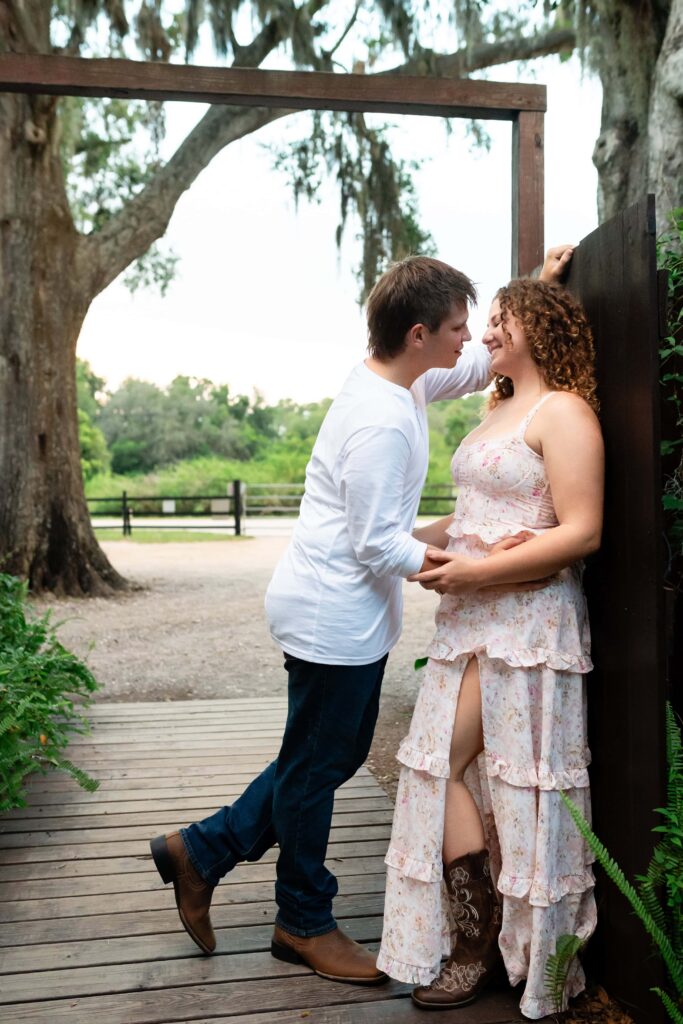 Couple smiling at each other under oak trees while holding hands. A sweet and relaxed St Pete engagement photo showing how awkward couples can look natural on camera.