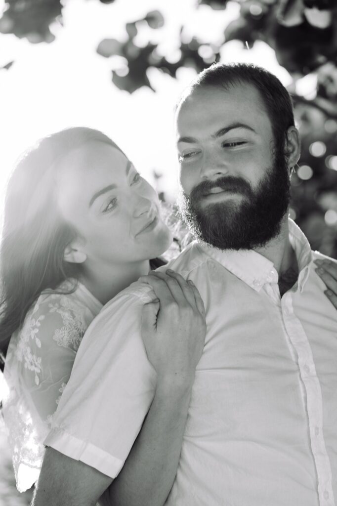 Black and white close-up of a woman smiling at her fiancé while holding onto his shoulders. A sweet, candid St Pete engagement photo showing how awkward couples can relax and enjoy the moment.
