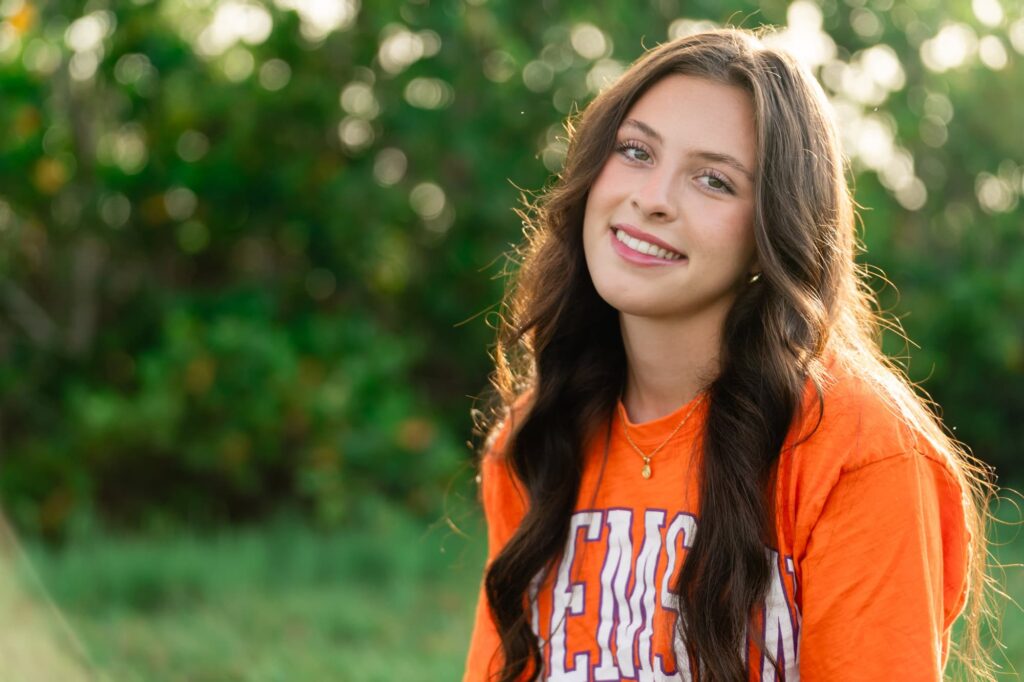 High school senior smiling during her portrait session in St Pete, wearing a Clemson shirt