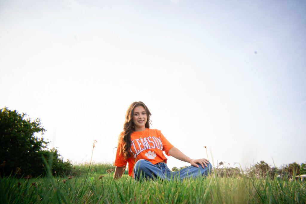 Senior portrait of teen girl sitting in tall grass at Fort De Soto Park