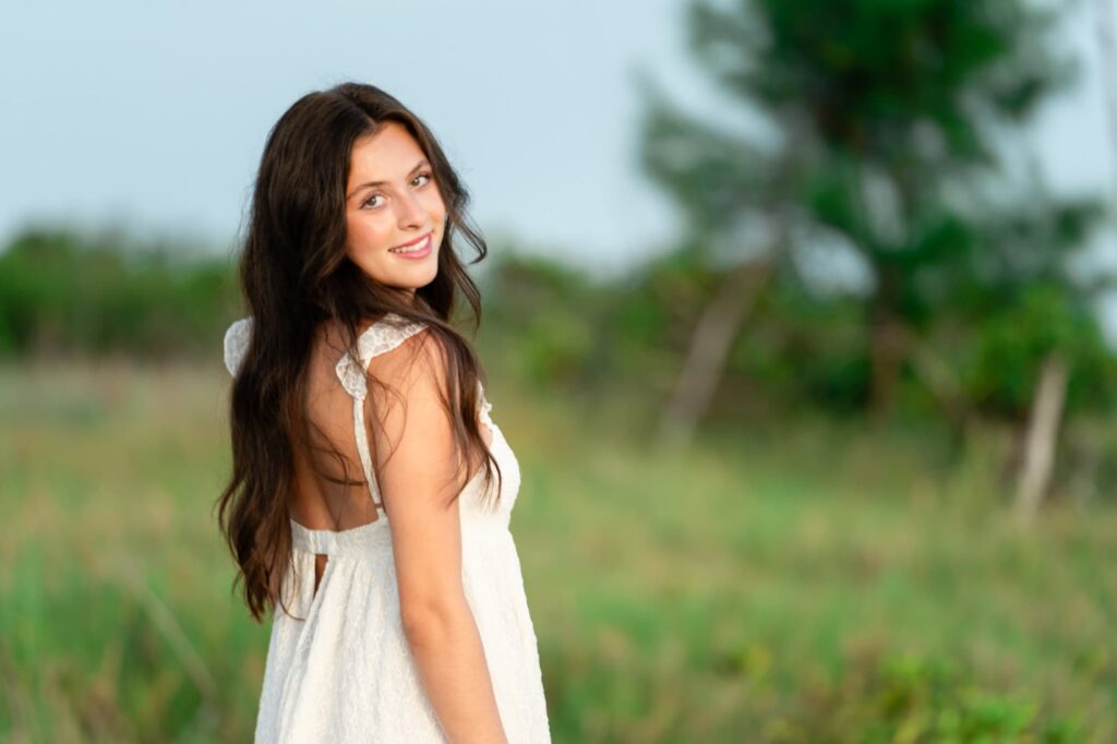 Smiling high school senior in a white dress at Fort De Soto Park in St Pete