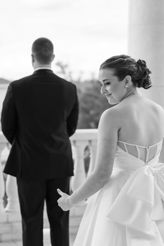 Bride smiling before first look moment with groom on outdoor balcony, captured by St. Pete area wedding photographer Erin Vestal.