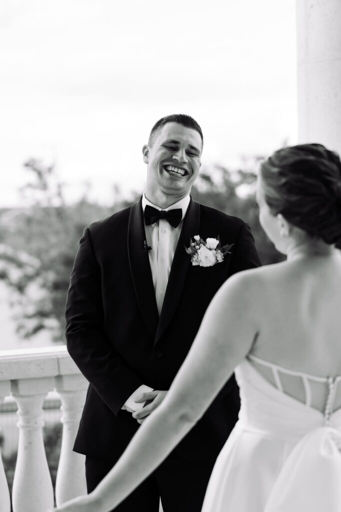 Groom smiling and laughing as he sees bride for the first time during first look, photographed by Erin Vestal in the Tampa Bay area.