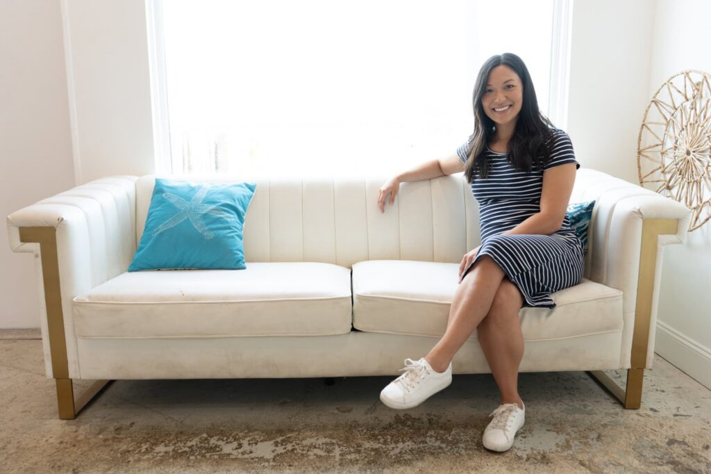 Tampa wedding planner Audra from Til Death Weddings & Design sitting on a white sofa with teal pillows, photographed by Erin Vestal Photography.