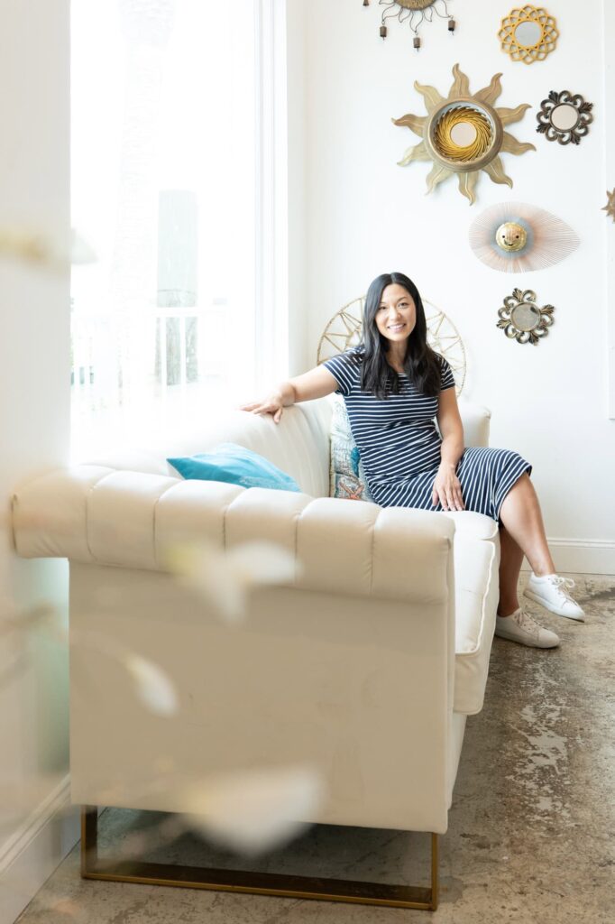 Audra, founder of Til Death Weddings & Design, relaxes on a white sofa in a light-filled Tampa studio, photographed by Erin Vestal Photography.