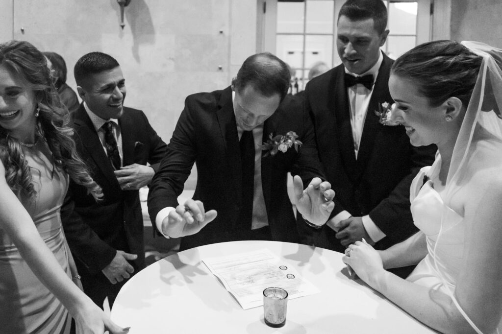 Wedding party cheering and laughing as witness signs marriage certificate, captured candidly by Erin Vestal Photography.