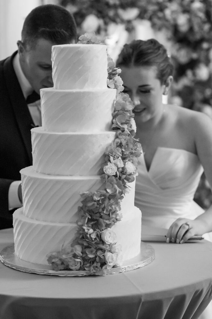 Close-up of white tiered wedding cake decorated with cascading flowers during reception, photographed by Erin Vestal.