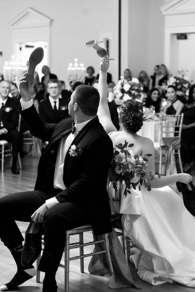 Bride and groom playing the wedding shoe game surrounded by guests during reception, photographed by St. Pete wedding photographer Erin Vestal.