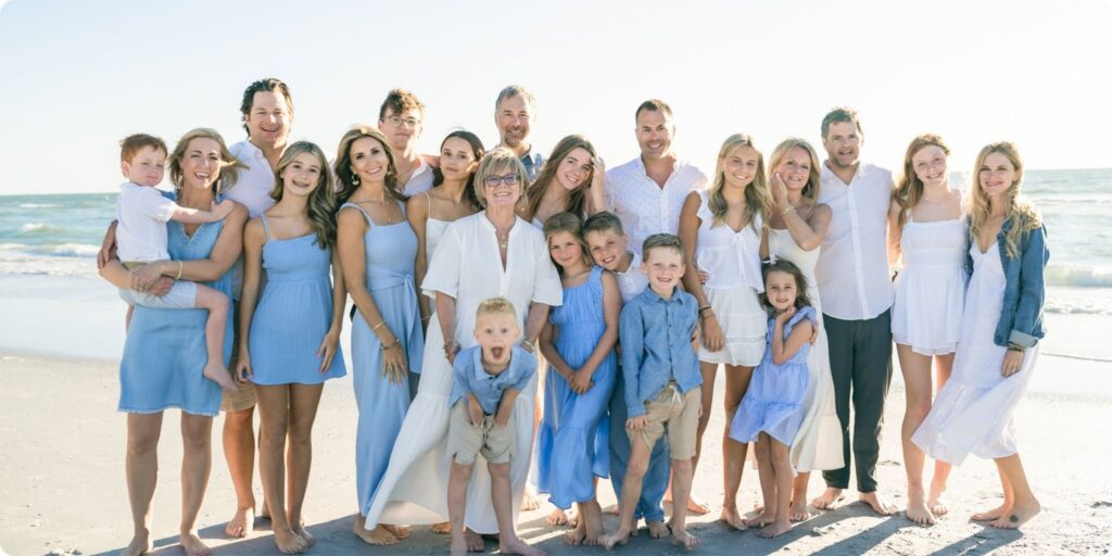 Large family group smiling together on the beach during a bright and breezy holiday family photo session in St. Petersburg, Florida.