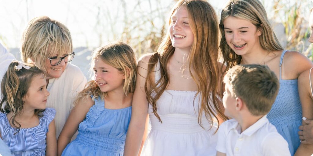 Grandmother surrounded by her grandchildren, all laughing and sharing a moment together during a relaxed St. Pete Beach family session.
