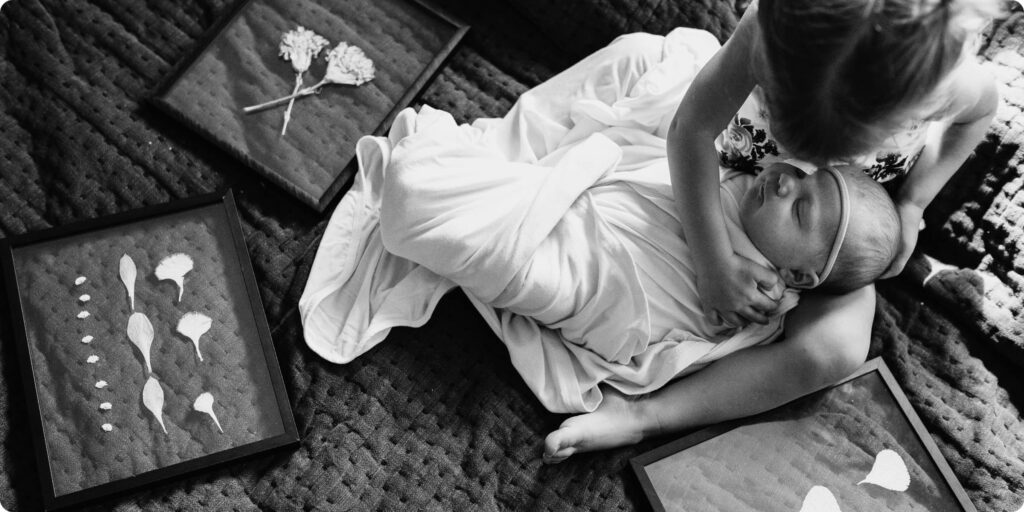 Newborn baby surrounded by framed pressed florals honoring pregnancy losses, photographed during in-home newborn session in St. Petersburg Florida