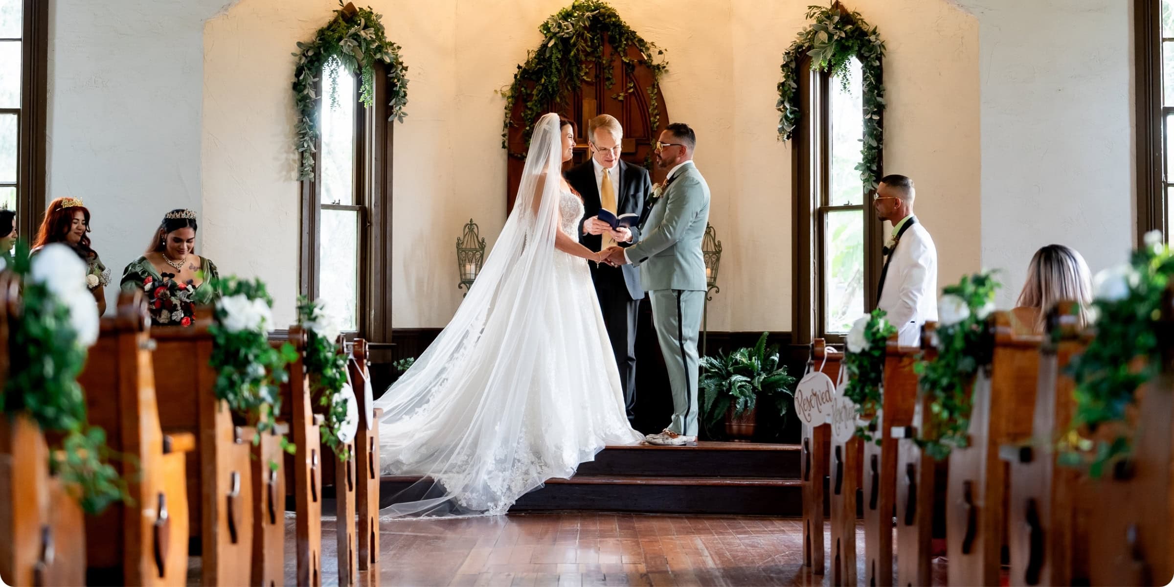 Bride and groom exchanging vows at Historic Andrews Memorial Chapel in Dunedin Florida, surrounded by wooden pews and tall windows with natural light