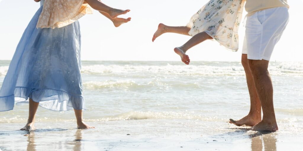Parents swinging their daughters at the water's edge during a spring break family photo session at St. Pete Beach