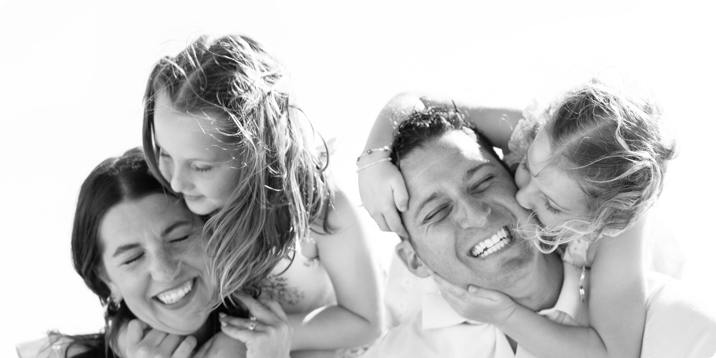 Family of four laughing together on the beach during a St. Pete spring break family photo session