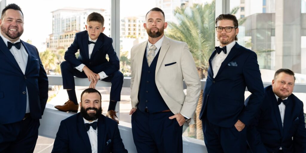 Groom and groomsmen portraits at Opal Sands Resort Clearwater Beach with palm trees and Gulf Coast skyline visible through windows